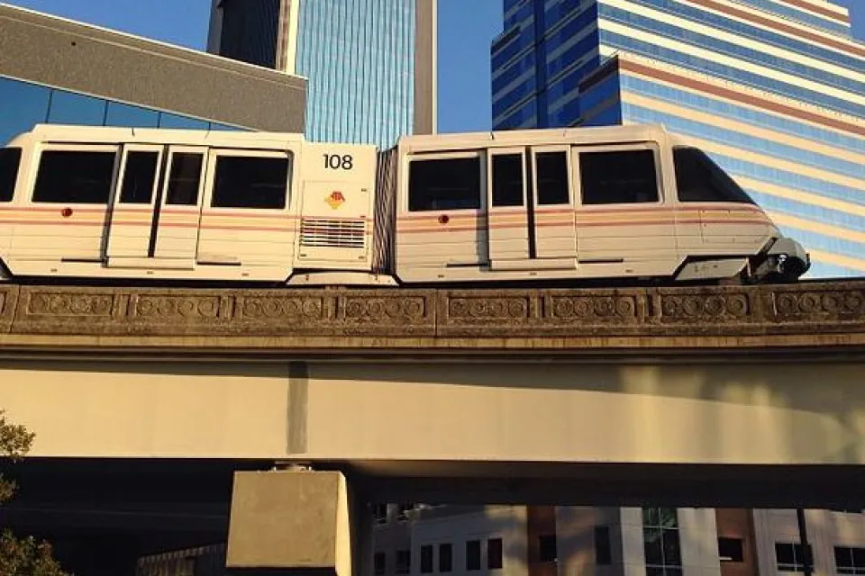 Jacksonville Skyway monorail train passing on elevated rail in front of downtown buildings